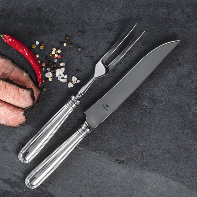 a knife and fork next to a piece of meat